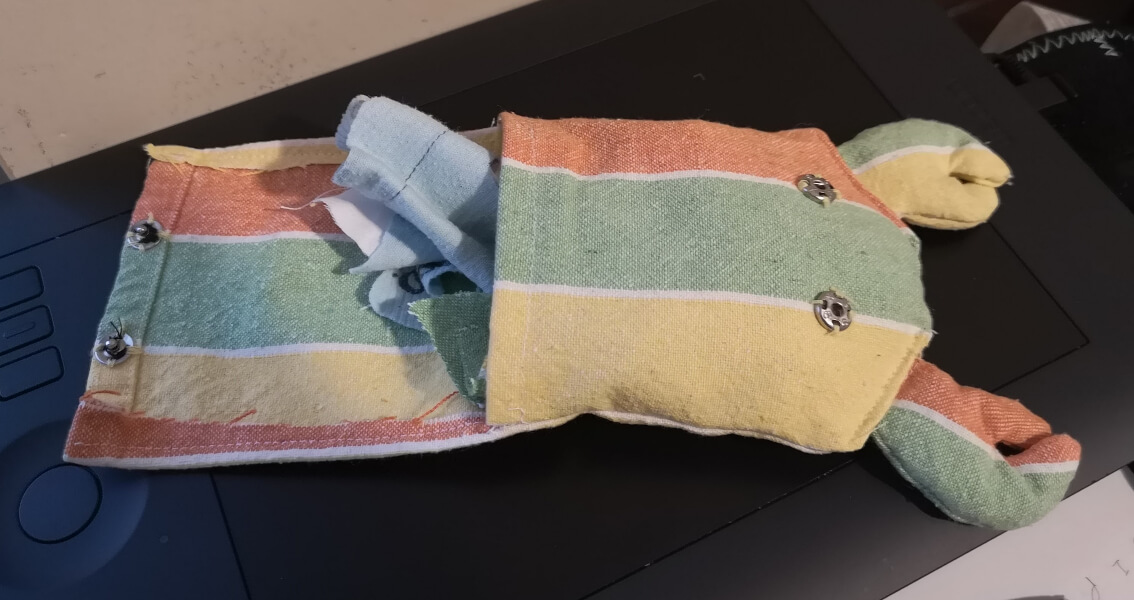 the crab pouch, open to show its snap fasteners. a scrap of fabric is poking out of the top